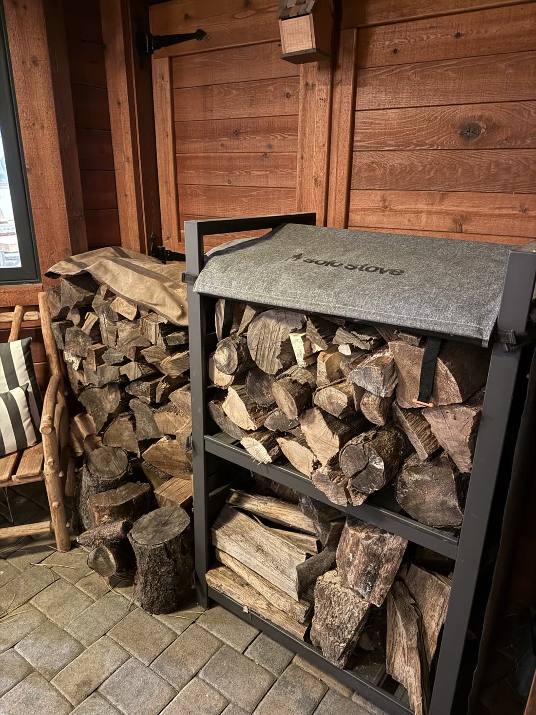 Firewood stacked on the porch rack under a cover